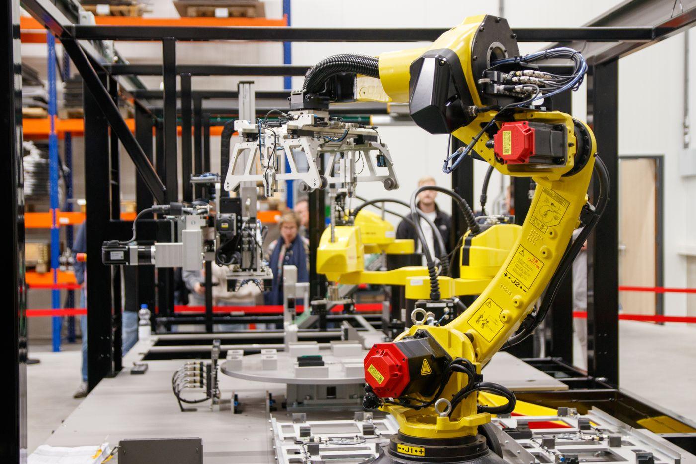 Yellow six-axis industrial robot working on an automated production cell